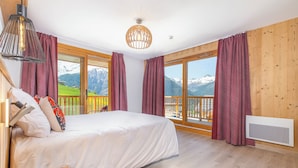 Une chambre avec un lit, une fenêtre donnant sur les montagnes et un plancher en bois.