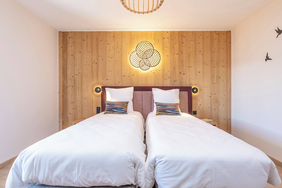 Un lit double avec une tête de lit en bois et un luminaire mural original.