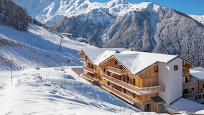 Un chalet en bois doté d’un balcon, situé au pied d’une montagne enneigée.