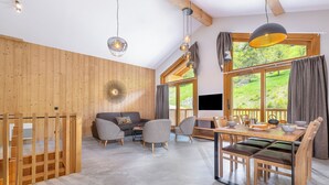 Un intérieur moderne avec un mur en bois, un coin repas comprenant une table et des chaises, et un canapé.