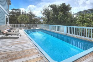 Relax by the pool surrounded by lush greenery and comfortable lounge chairs.