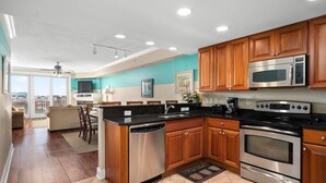 A modern kitchen with wooden cabinets, stainless steel appliances, and a dining area with a view.