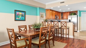 A dining area with a wooden table and chairs, a small island with a sink, and wooden cabinets in the background.