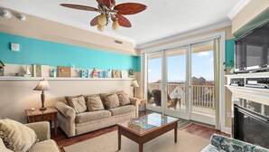 A living room with a beige sofa, a wooden coffee table, and a teal accent wall.