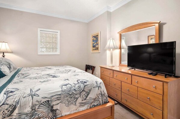 A bedroom with a bed, a dresser, a television, and two lamps.