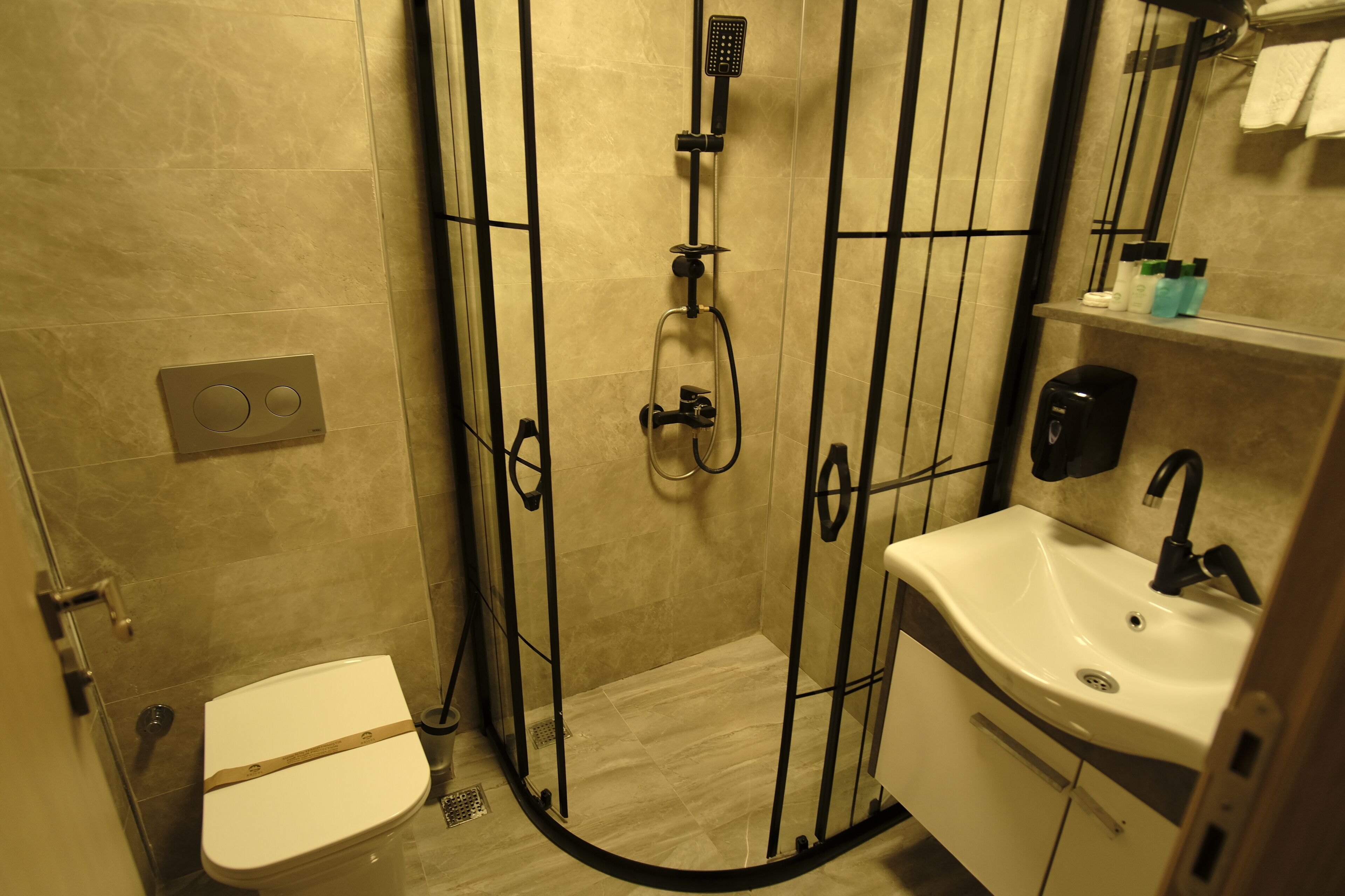 Un baño con inodoro, cabina de ducha, lavabo y espejo.