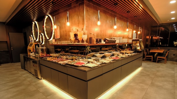 Een buffetgedeelte met diverse gerechten, een koffieapparaat en een zithoek met tafels en stoelen.