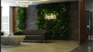 Een moderne lobby met een groene wand, een bord met de tekst 'hello', een bank en een marmeren salontafel.