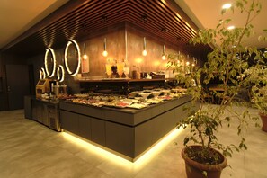 A modern bar area with a central island displaying various food items and a bar counter.