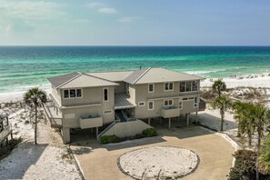 Une maison de deux étages située en bord de mer, dotée d’une terrasse et d’un jardin circulaire, et offrant une vue sur l’océan.