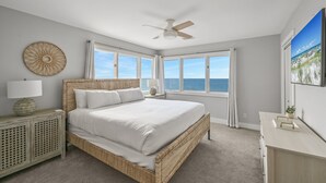 A bedroom with a large bed, a ceiling fan, and a view of the ocean through the windows. - Gulf-Front with Private Deck and Water Views (Miramar Beach)