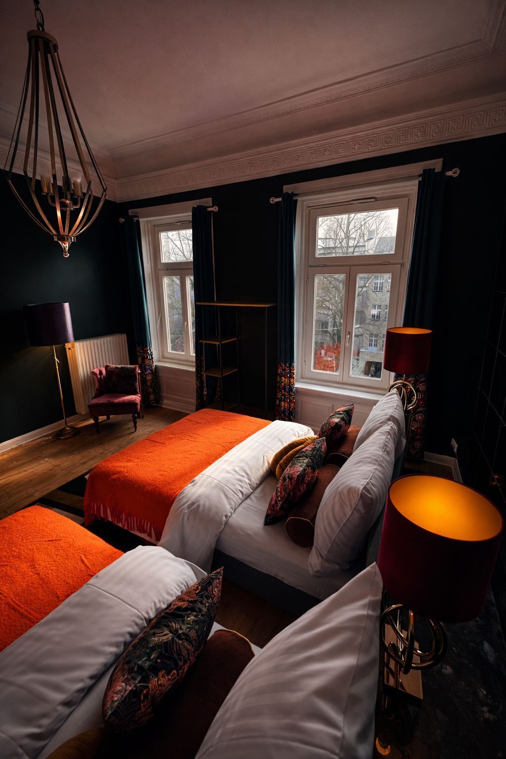 A hotel room with a large bed, a chair, a floor lamp, and a window with curtains.