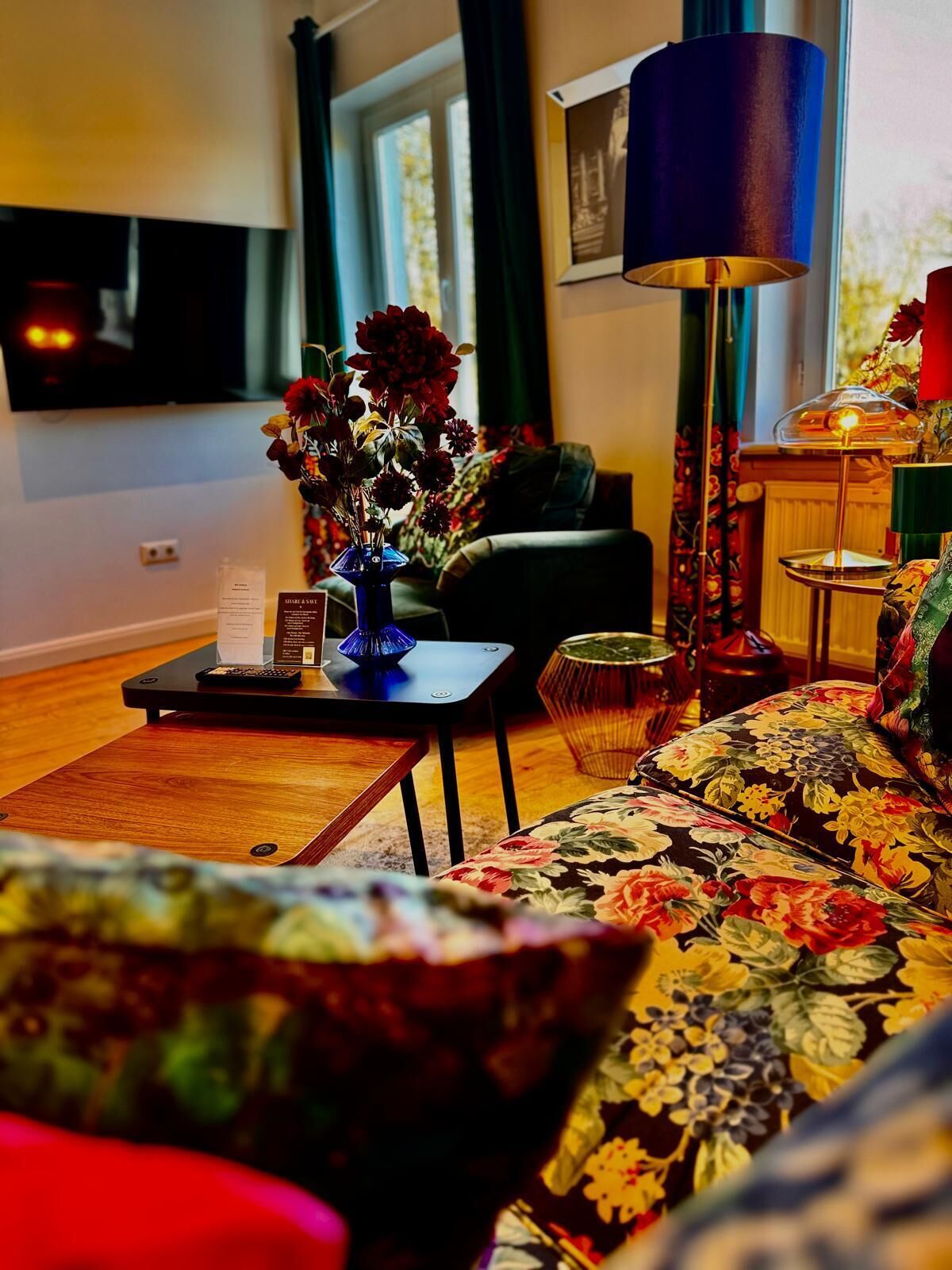Ett vardagsrum med en soffa, ett soffbord, en lampa och en vas med blommor.