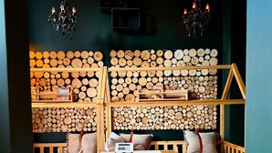 A cozy bedroom with a bed, a wooden table, and a chair. There is a large wooden headboard with logs and a cowhide rug on the floor. - Sleephotels Alsterroom (Hamburg)