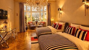 A spacious bedroom with a large bed, a chandelier, and a view through a window. - Sleephotels Alsterroom (Hamburg)