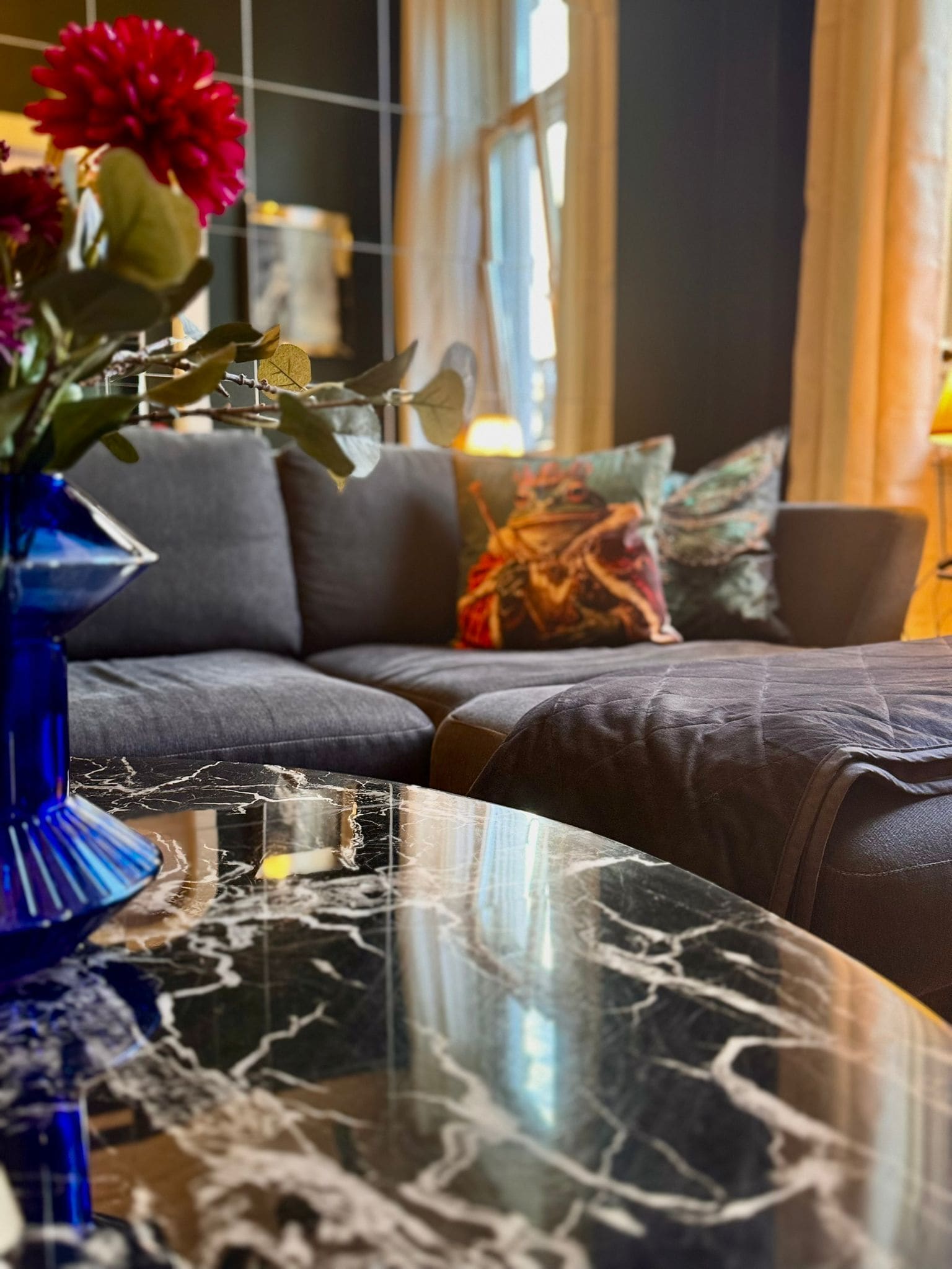 A modern living room with a sofa, a marble coffee table, and a vase with flowers.