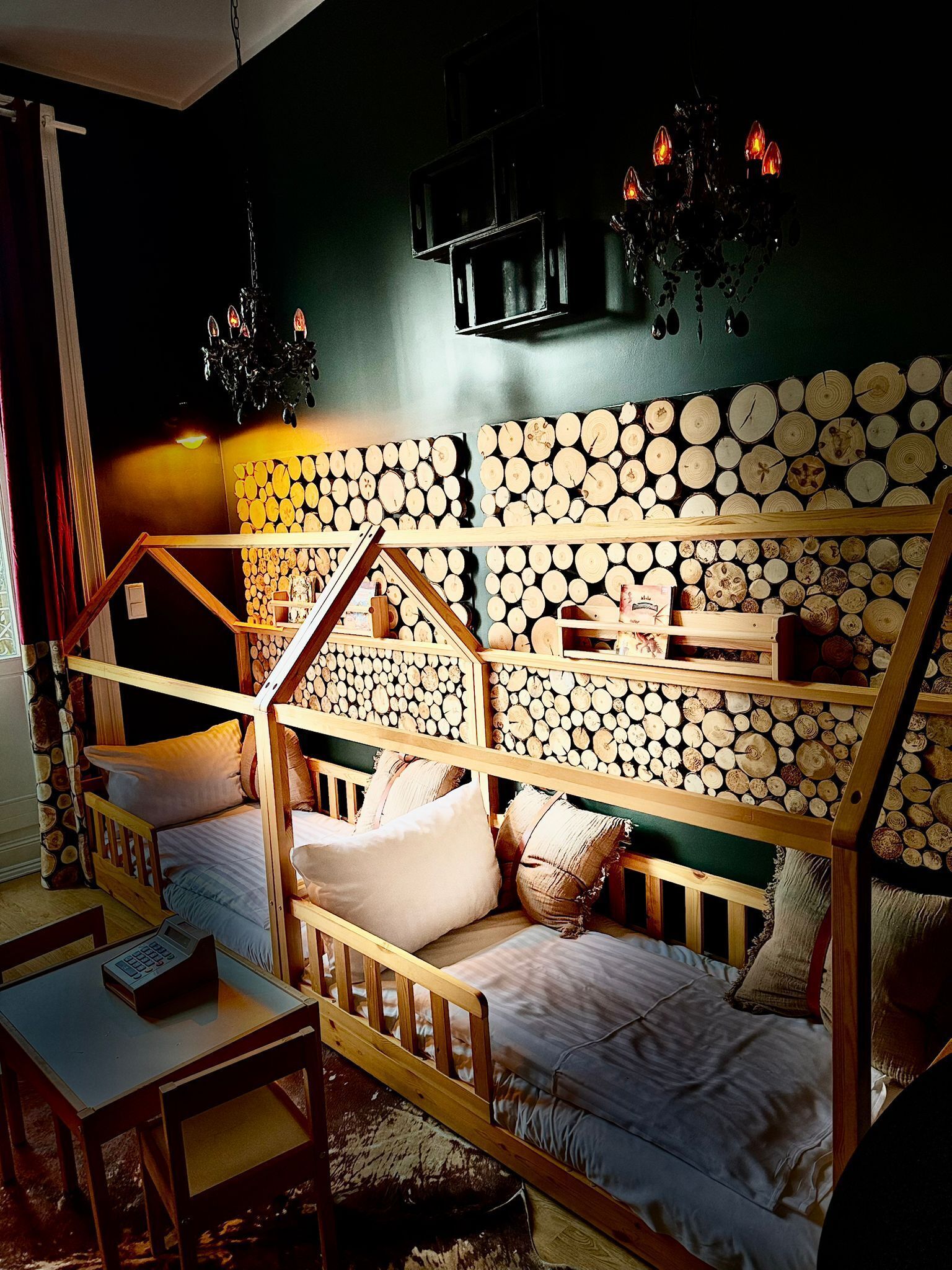 Una habitación acogedora con una cama litera, leños en la pared, una mesita y un televisor sobre la cama.