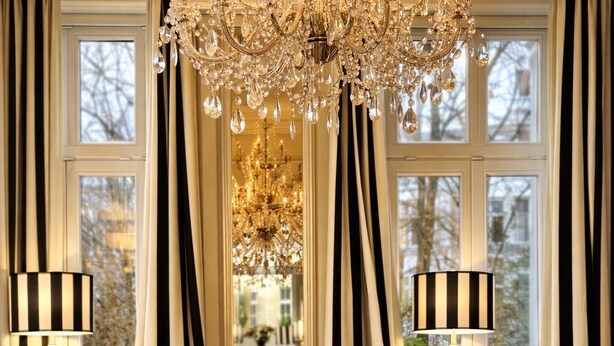 A luxurious living room with a large sofa, a glass coffee table, and a chandelier. - Sleephotels Alsterroom (Hamburg)