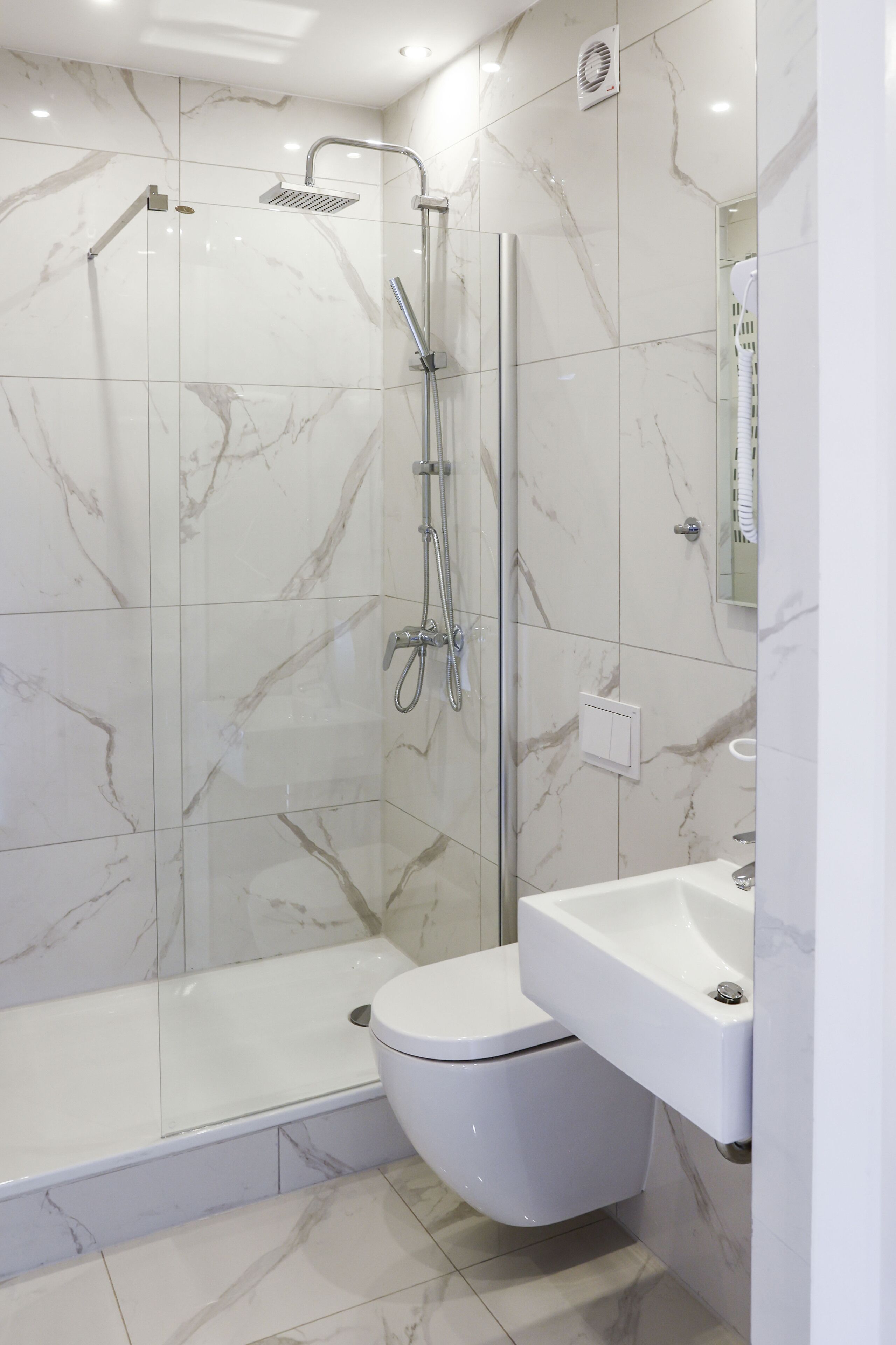 Ein modernes Badezimmer mit einer gläsernen Duschkabine, einer weißen Toilette und einem Waschbecken.