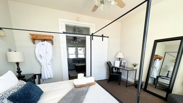 Habitación de hotel con una cama grande, un escritorio, una silla, un espejo y una puerta que da a un balcón.