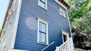 A two-story house with a white front porch and a small staircase leading to the entrance. - South Shore Condo @ Bayfield Guest House (Bayfield)
