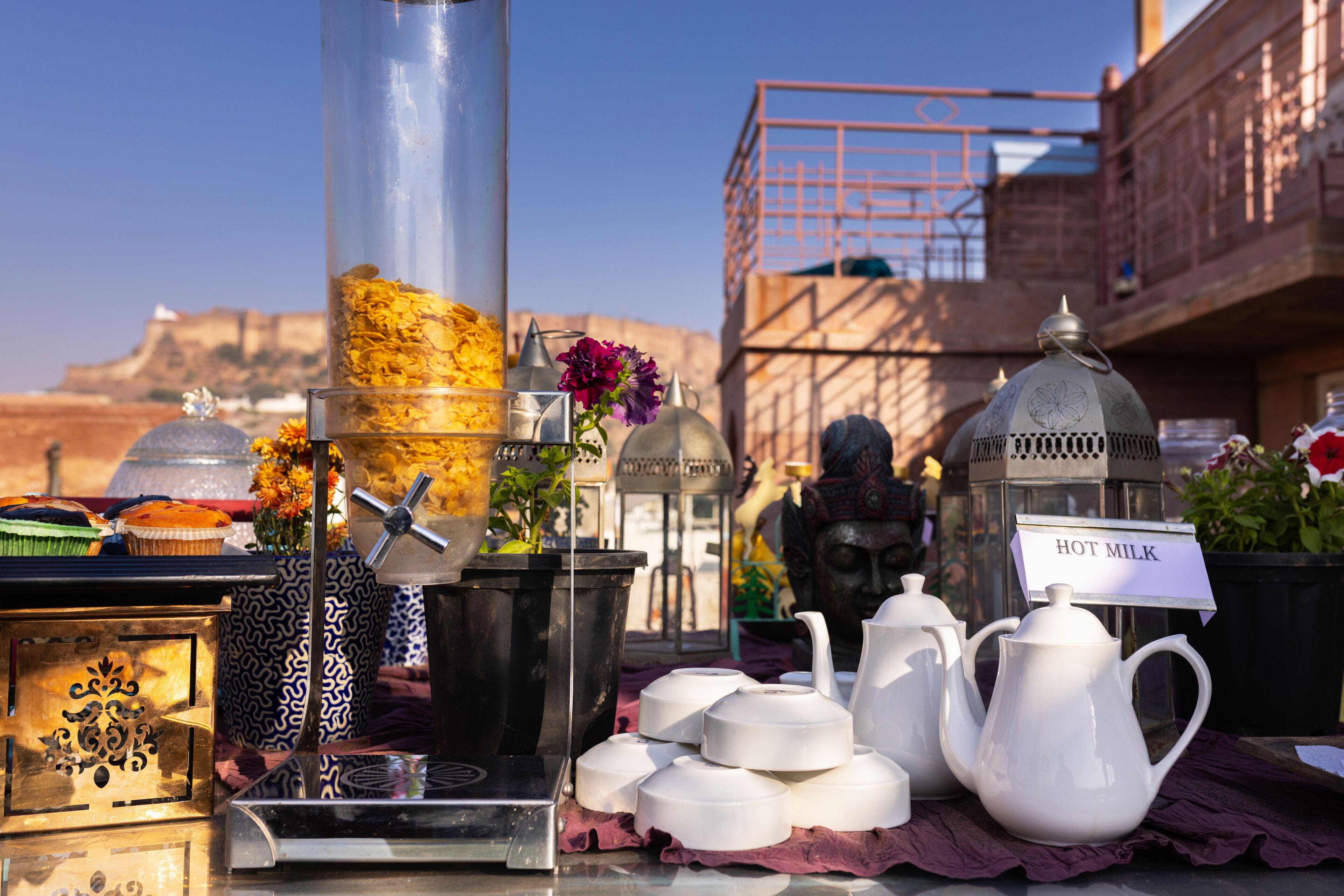 A table with tea sets, a sign reading "HOT MILK," and a lantern.