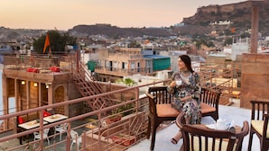 A terrace with a view of a cityscape, including a hill and buildings.