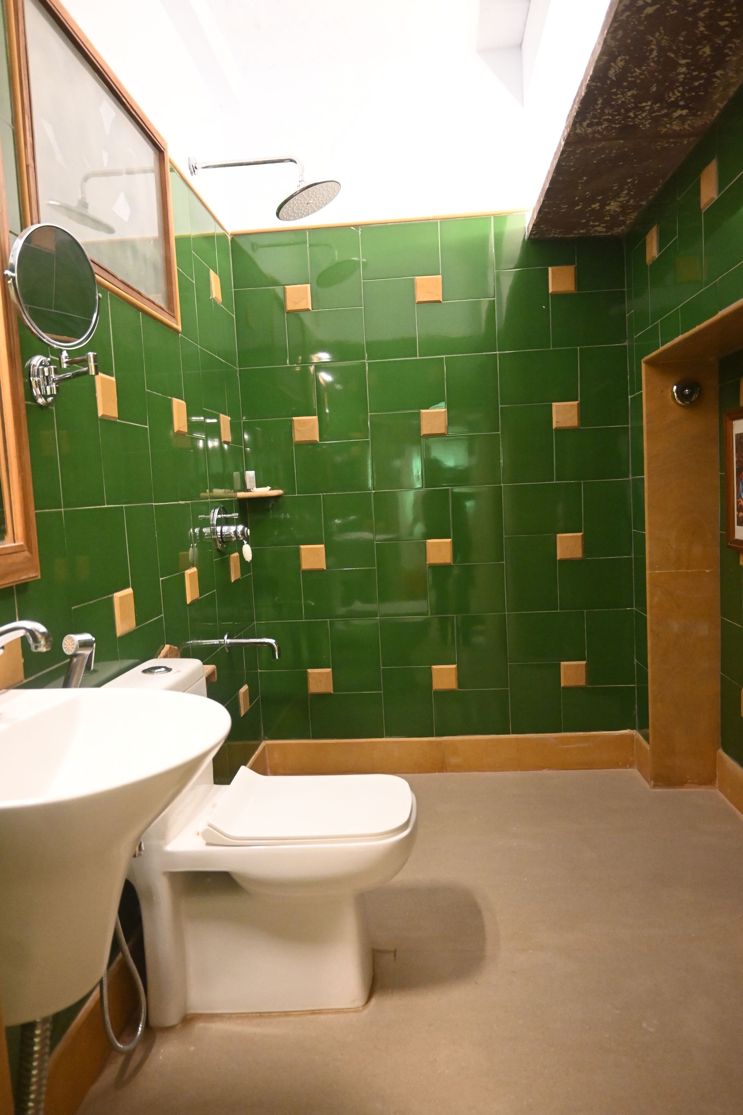 A bathroom with green tiled walls, a white sink, and a toilet.