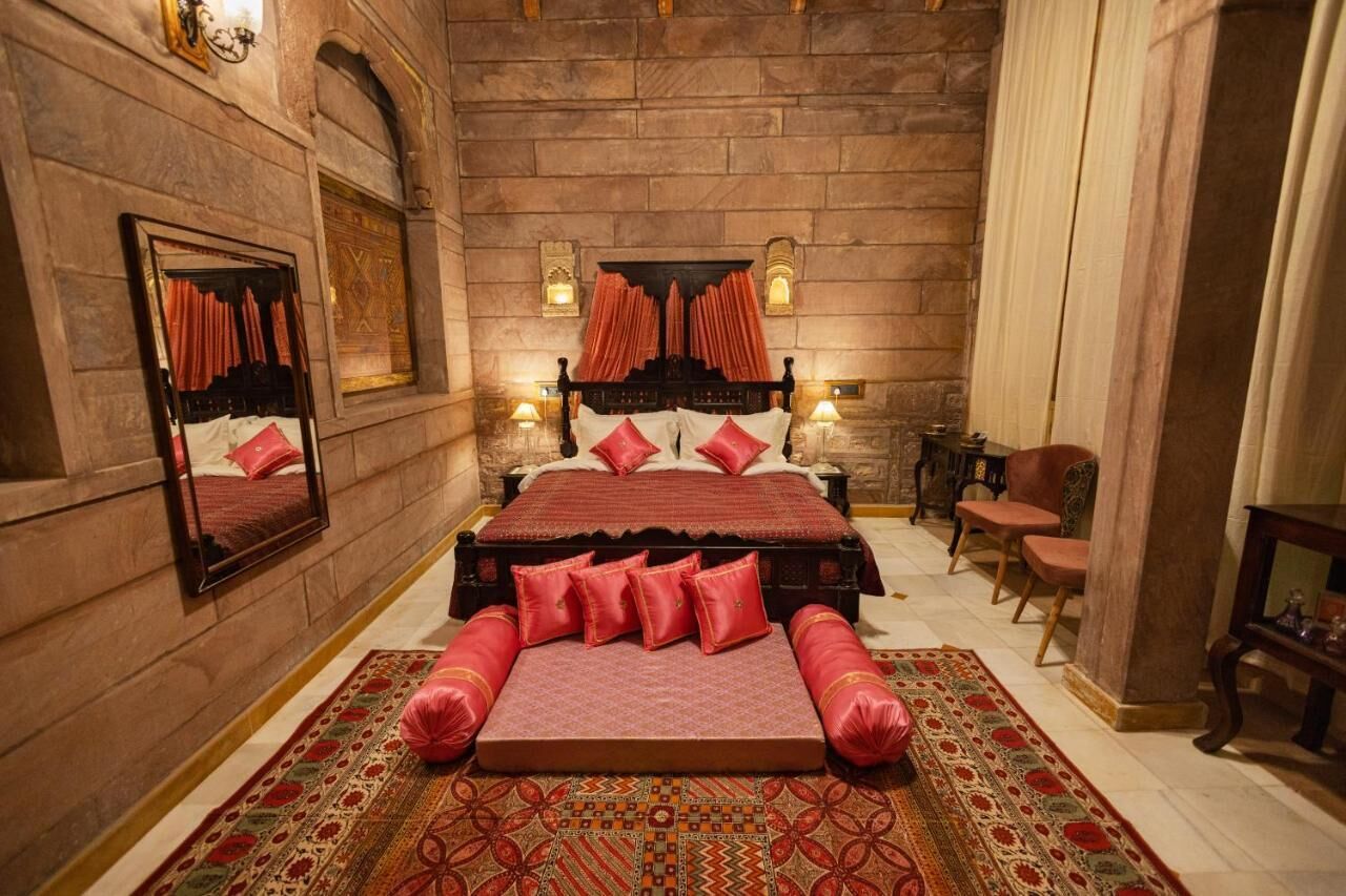 Een slaapkamer met een groot bed, een spiegel, een open haard en een vloerkleed.