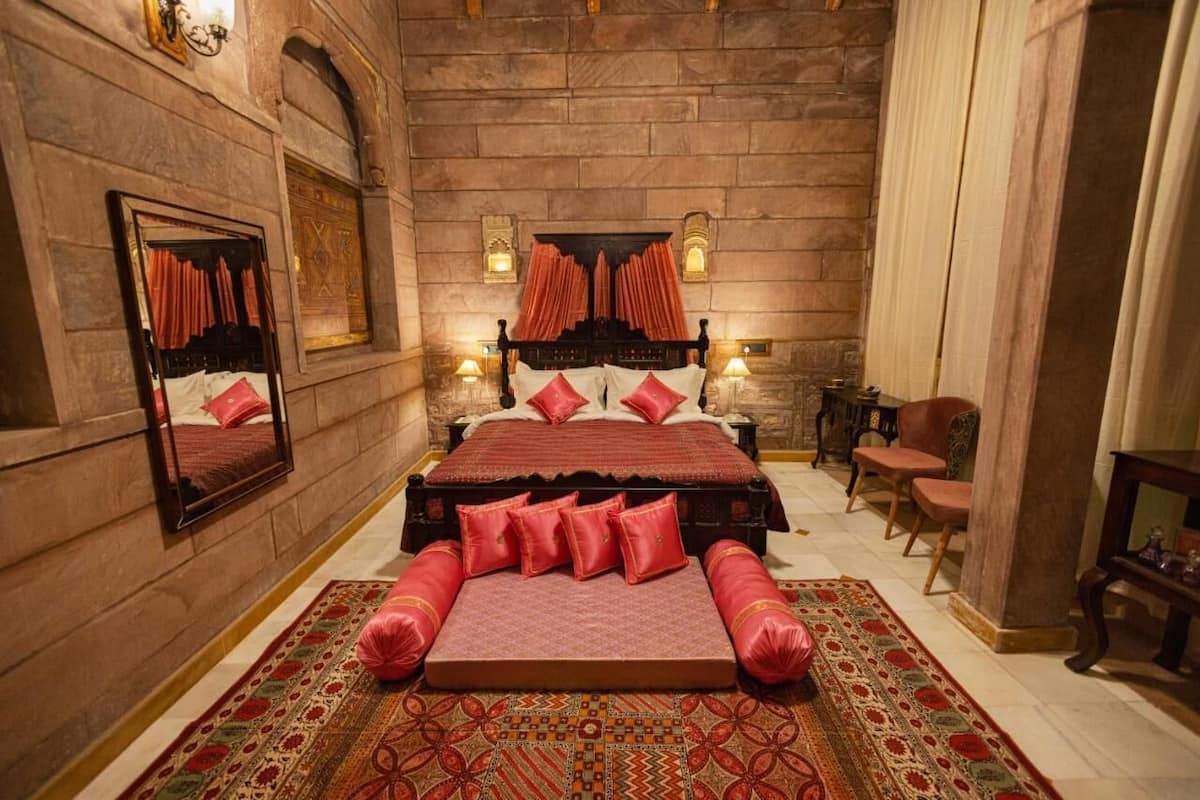 A bedroom with a large bed, a mirror, a fireplace, and a carpet.