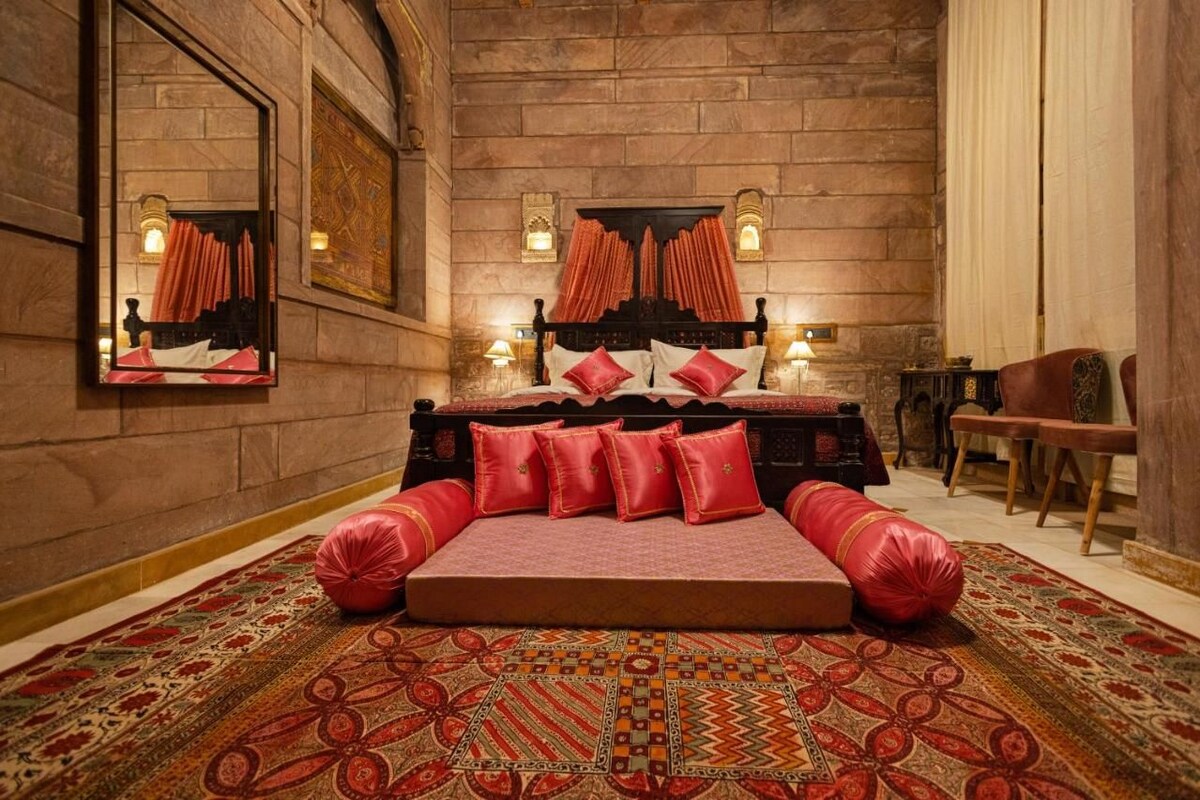 A bedroom with a large bed, a mirror, and a carpet.