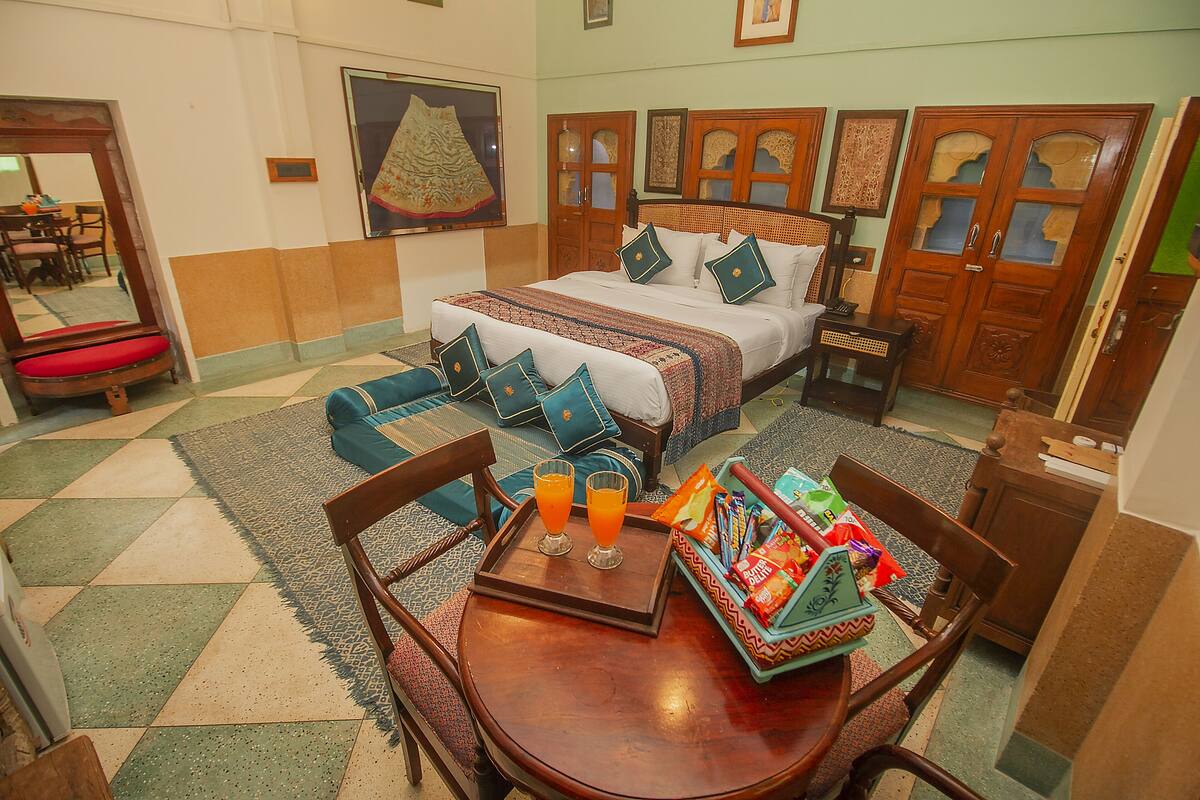 Ein Hotelzimmer mit Bett, Esstisch mit Stühlen, einem Tablett mit Orangensaft und einer kleinen Speiseplatte.