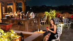 An outdoor dining area with a bar, seating, and decorative plants.
