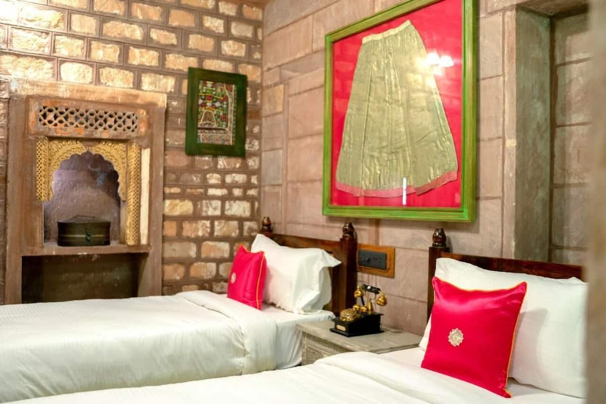 A hotel room with two beds, a fireplace, a framed picture, and a mirror.