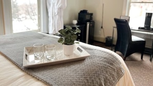 Hotelkamer met een bed, bureau, televisie en dienblad met glazen en een plant.