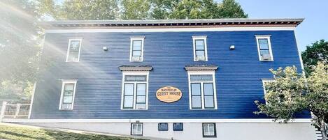 A two-story building with a blue exterior, a sign reading "The Bayfield Guest House," and a white trim around the windows.