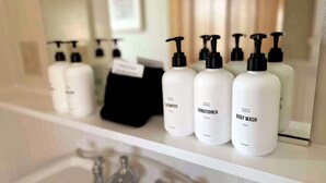 Une étagère de salle de bain avec trois bouteilles de gel douche, d’après-shampoing et de shampoing.