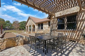 Situated in a landscaped area, this traditional building features a covered patio with a table and chairs.