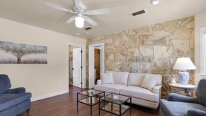 Un ampio soggiorno con parete in pietra, una ventola a soffitto e un quadro di grandi dimensioni.