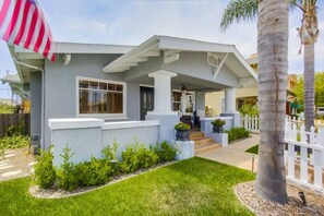 A residential house with a covered porch, a front yard with a palm tree, and a white picket fence. - Cozy 1920's Craftsman bungalow, Hillcrest/Mission Hills (San Diego)