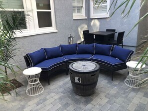 A blue sectional sofa with white accents, two round white tables, and a wooden barrel in a patio area. - Cozy 1920's Craftsman bungalow, Hillcrest/Mission Hills (San Diego)