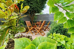 Eine Terrasse im Freien mit Holzmöbeln und üppigem Grün.