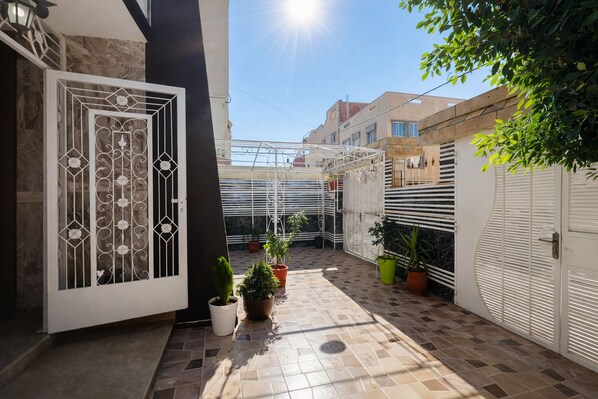 A courtyard with a tiled floor, potted plants, a metal gate, and a white door. - Luxury villa with all comforts, close to Oujda town center (Oujda)