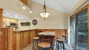 Una cocina con armarios de madera, microondas y una barra con taburetes.