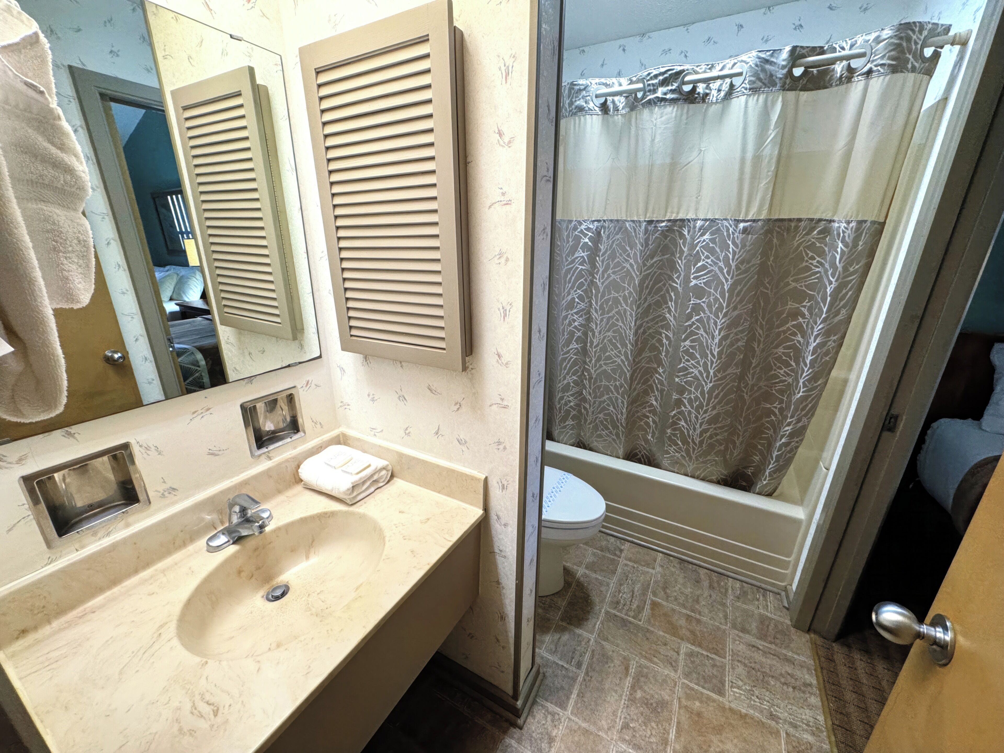 Une salle de bain équipée d’un lavabo, d’un miroir, d’un porte-serviettes et d’un rideau de douche.