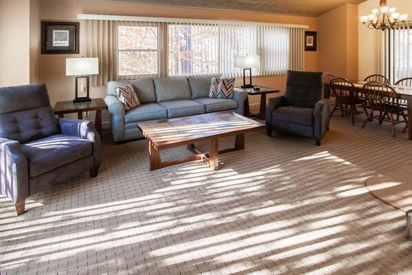 A living room with a sofa, two armchairs, a coffee table, and a dining area with a table and chairs.