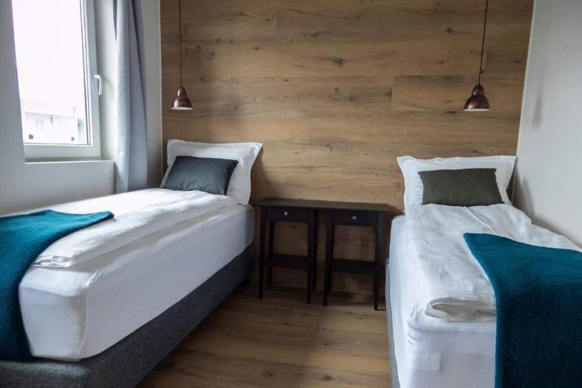 Ein Zimmer mit zwei Betten, einem kleinen Tisch und einer Holzwand.