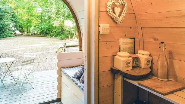 Ein gemütliches Holzhaus mit einer Bank, einem Tisch, einer herzförmigen Dekoration und einer Teeflasche.
