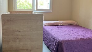 Une chambre à coucher avec un lit, un bureau, une fenêtre et un luminaire suspendu.