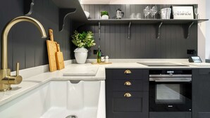 Una cocina moderna con un lavamanos blanco, armarios negros y un horno empotrado.